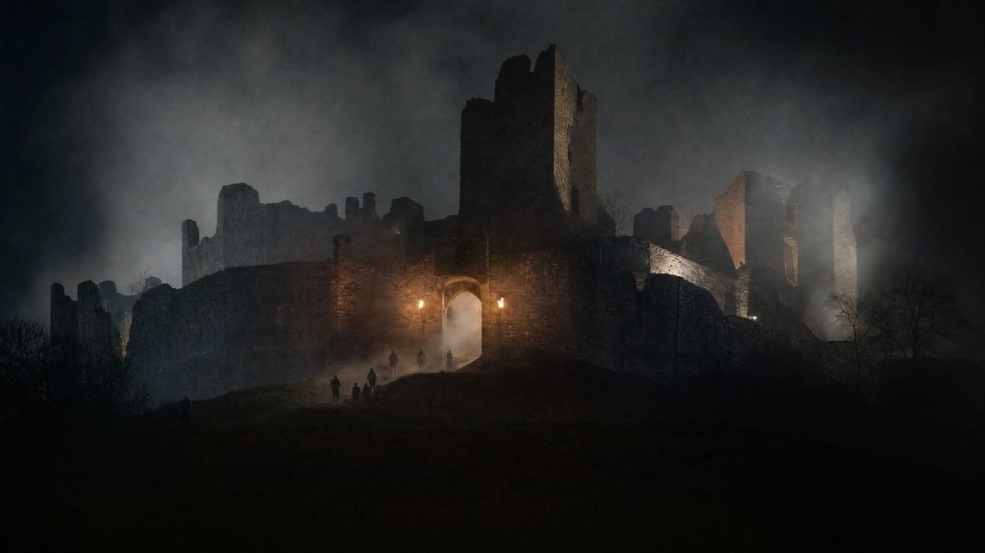 Beleuchtete Burgruine bei Nacht, Nebel zieht durch das Tor, Besucher als Silhouetten