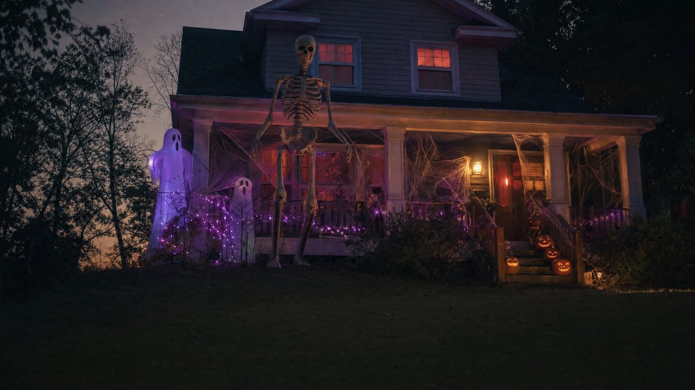 Amerikanisches Vorstadthaus mit riesigem Skelett im Vorgarten, Geisterfiguren und Lichterketten