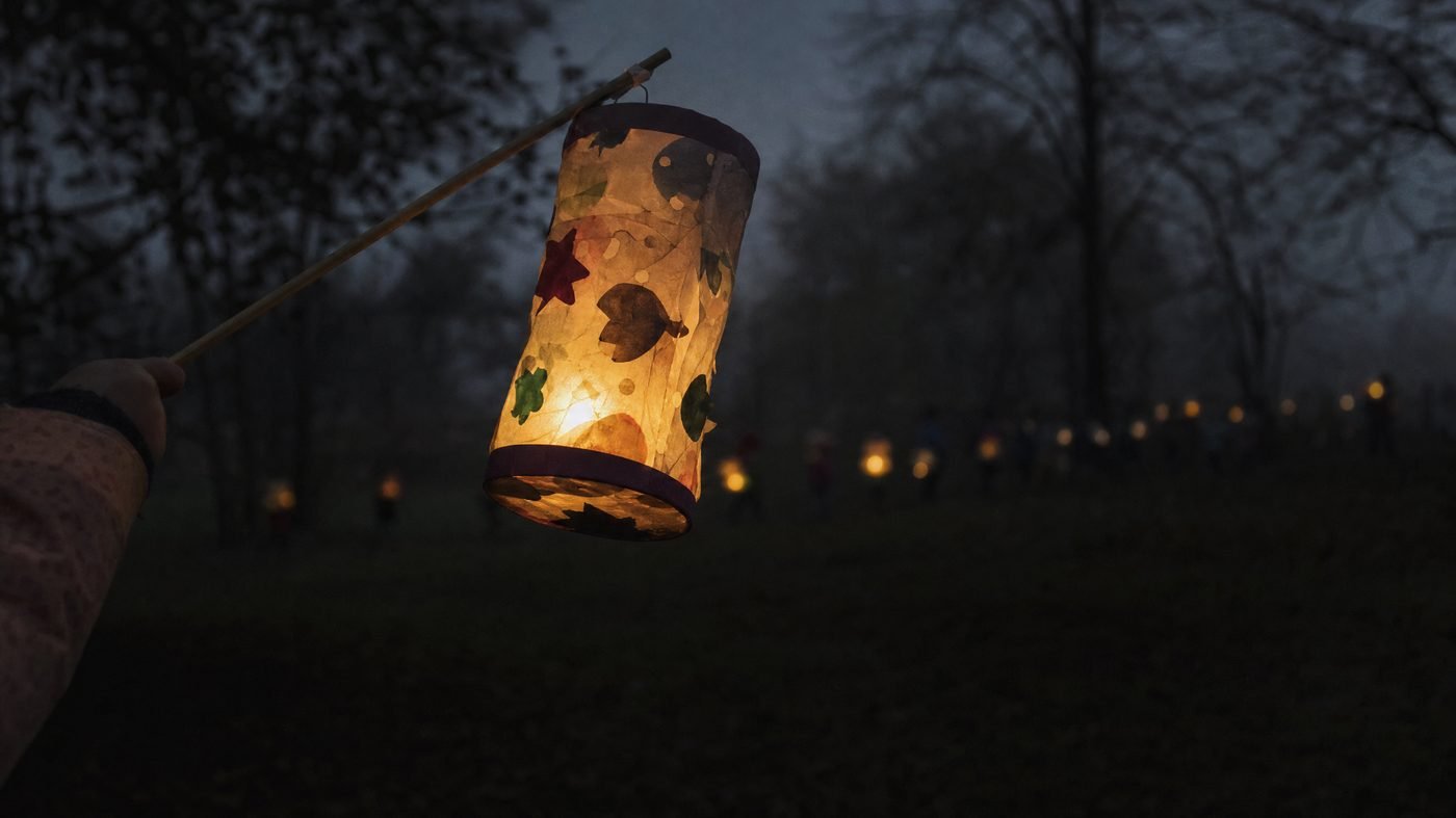 Selbst gebastelte Laterne leuchtet in der Dämmerung, im Hintergrund weitere Laternen im Nebel