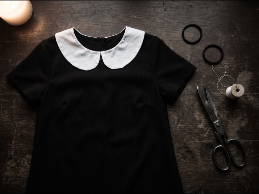 Schwarzes Kleid mit weißem Kragen aus Stoffrest, daneben zwei Haargummis