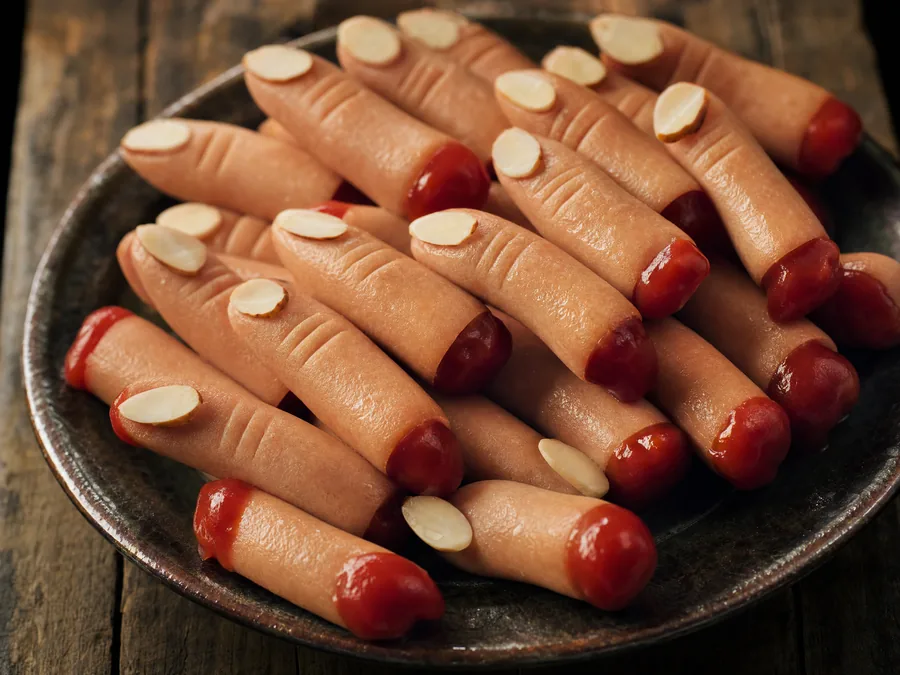 Wiener Würstchen mit eingeritzten Knöcheln und Mandelblättchen als Nagel, dazu Ketchup