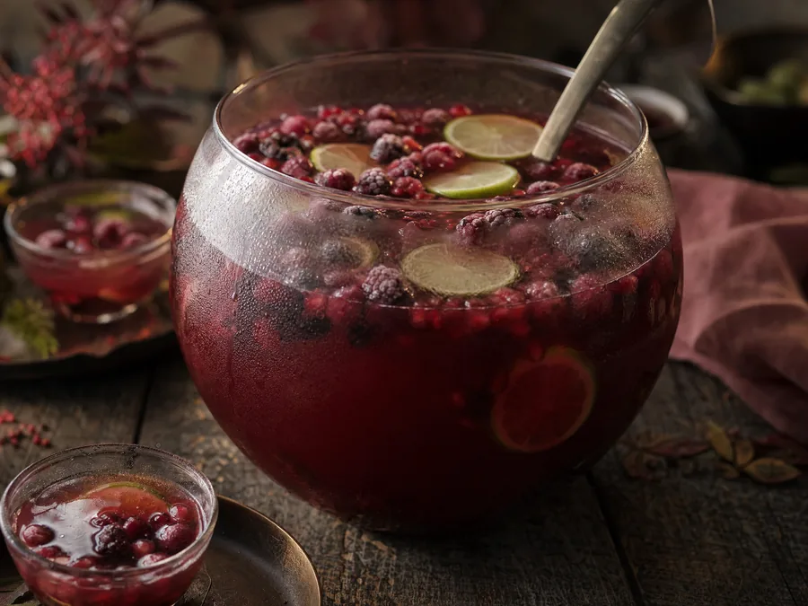 Tiefrote Bowle mit gefrorenen Beeren und Limettenscheiben