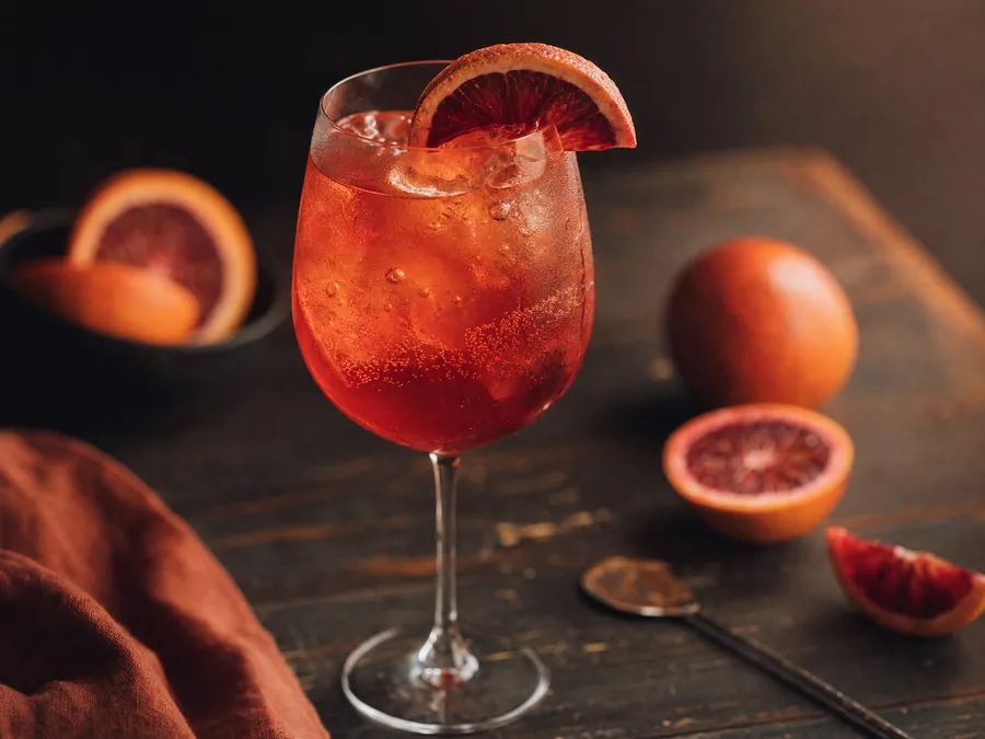 Blutorangen-Spritz im Weinglas mit Eis und Orangenscheibe
