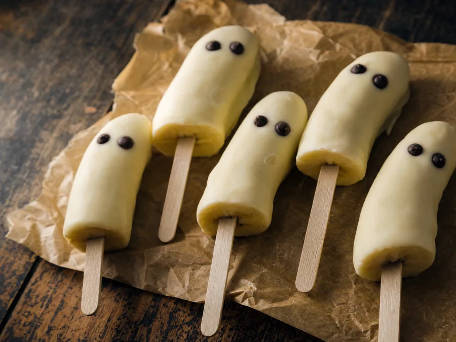 Halbierte Bananen mit weißer Schokolade überzogen und Schokotropfen als Augen