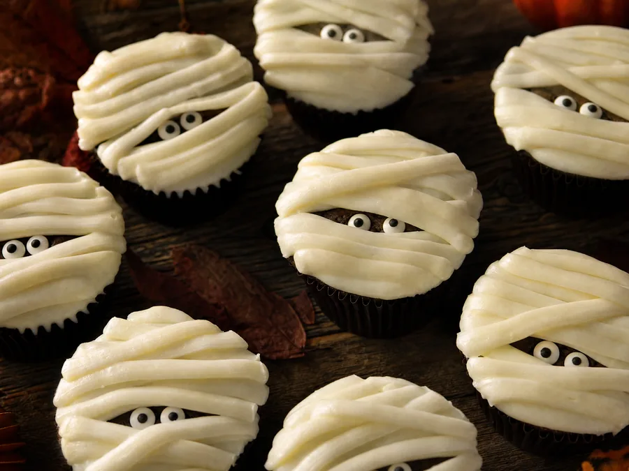 Cupcakes mit schrägen Frischkäsestreifen als Mumienbinden und Zuckeraugen