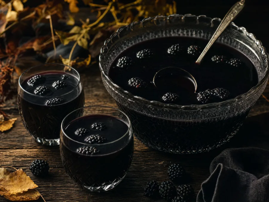 Tiefschwarze Bowle mit Brombeeren in einer Glasschüssel