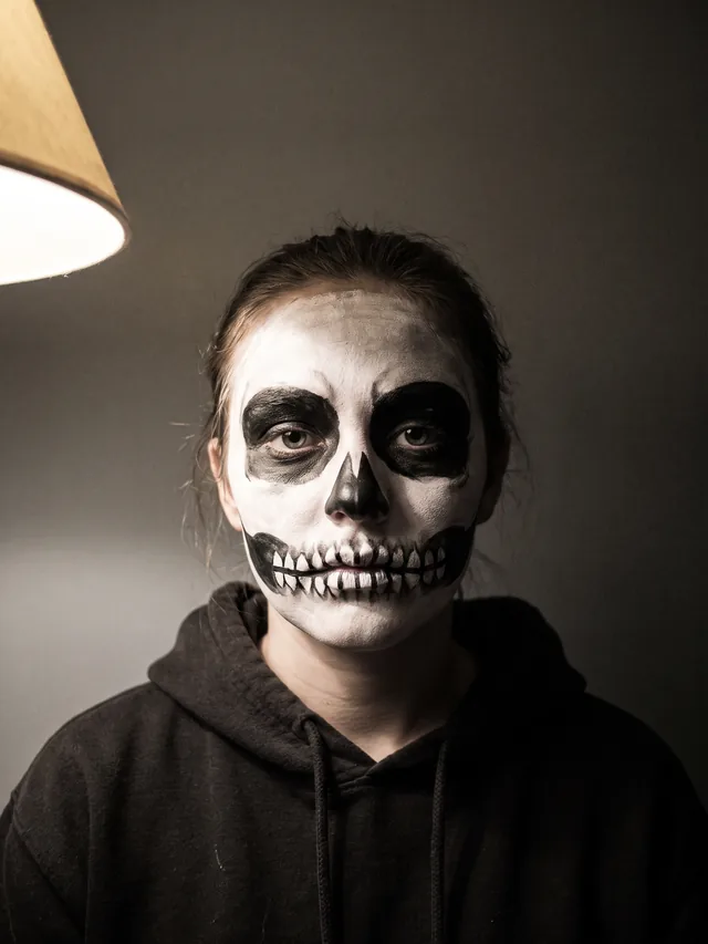 Als Totenkopf geschminkte Frau mit weißem Gesicht, großen schwarzen Augenhöhlen und einer Zahnreihe über beide Lippen